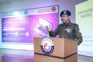 Police officer in uniform giving a talk at a wooden podium with Graphic Era Hill University seal, backdrop showing a Cyber Security Awareness banner.