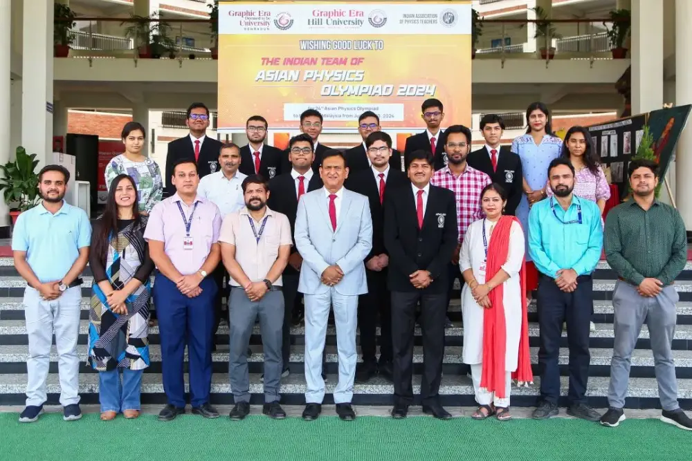 Group of students and staff posing on stairs in front of a banner for the Asian Physics Olympiad 2024.