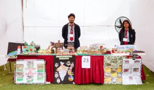 Two students stand behind a long display table filled with colorful livestock-breeds models and posters at a science-fair style exhibit.