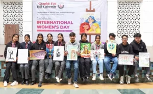 Group of students sitting on a bench, each holding their art pieces, in front of a banner for International Women's Day at campus event.