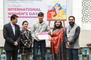 Group of five people posing for a certificate award at an International Women’s Day event with a banner in the background.