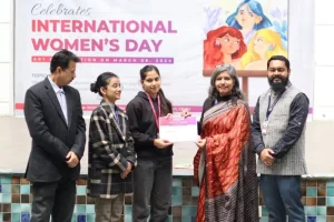 Group of five adults posing for a certificate presentation in front of a banner that says International Women's Day. (informative)