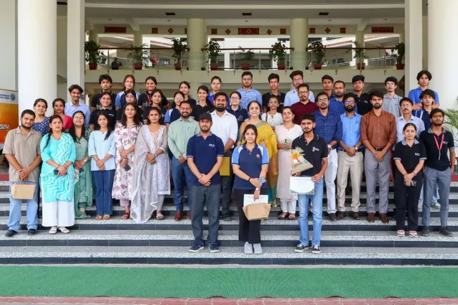 Group of students and staff posing on building steps for a group photo at an event.