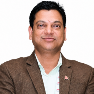 Dr. Bhagwati Prashad Chaudhary Portrait of a man wearing a brown blazer and light green shirt, smiling at the camera.