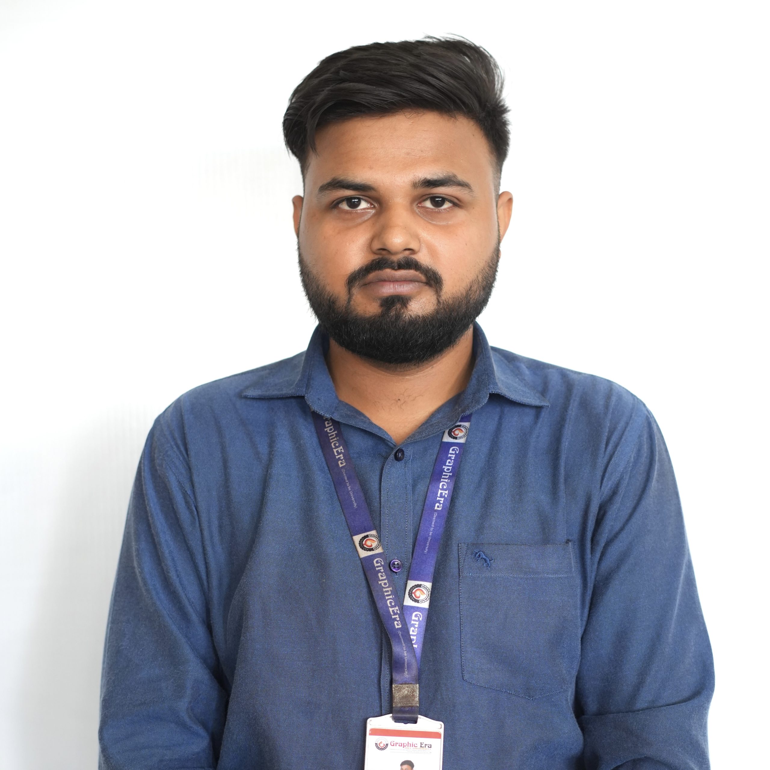 Mr Prateek Kumar 2 Portrait of a man in a blue shirt wearing a purple conference lanyard with a badge against a white background