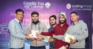 Presenter hands certificates and trophies to students on a stage with a purple university backdrop.