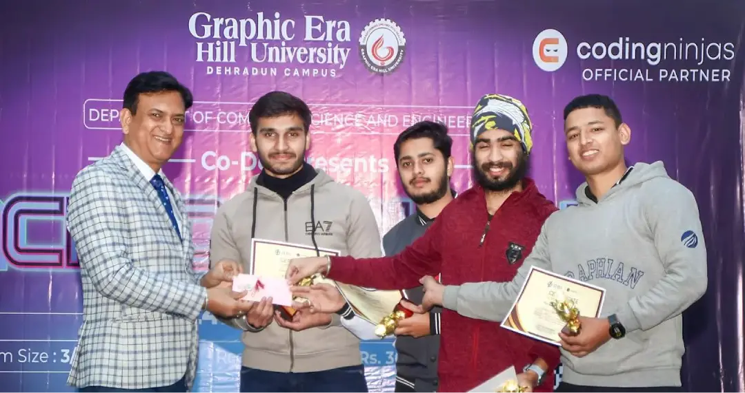 Presenter hands certificates and trophies to students on a stage with a purple university backdrop.