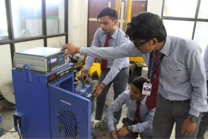 Three students in uniforms operate a blue lab machine, adjusting controls during a workshop session.