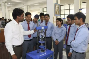Instructor demonstrates a material testing device to a group of engineering students in a lab setting.