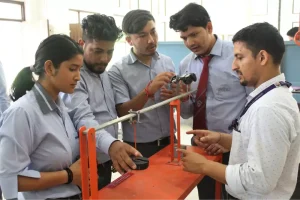 Group of students in uniform work on a lever-based lab setup with a sensor on an orange table.