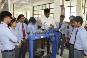Instructor demonstrates a blue metalworking machine to students in a campus workshop.
