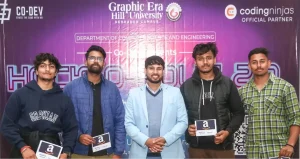 Group photo at a tech event with five men posing in front of a purple banner displaying Graphic Era Hill University and Coding Ninjas logos, each holding an award card with an Amazon logo.
