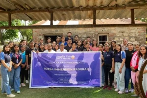 Group of students and faculty posing with a blue banner for Graphic Era Hill University Rural Immersion Program, MBA batch 2021–2023.