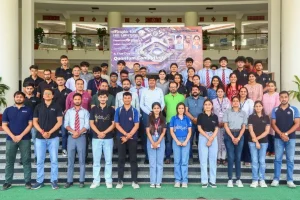 Large group of students and staff posing on stair steps in front of a banner for a quantum computing workshop.